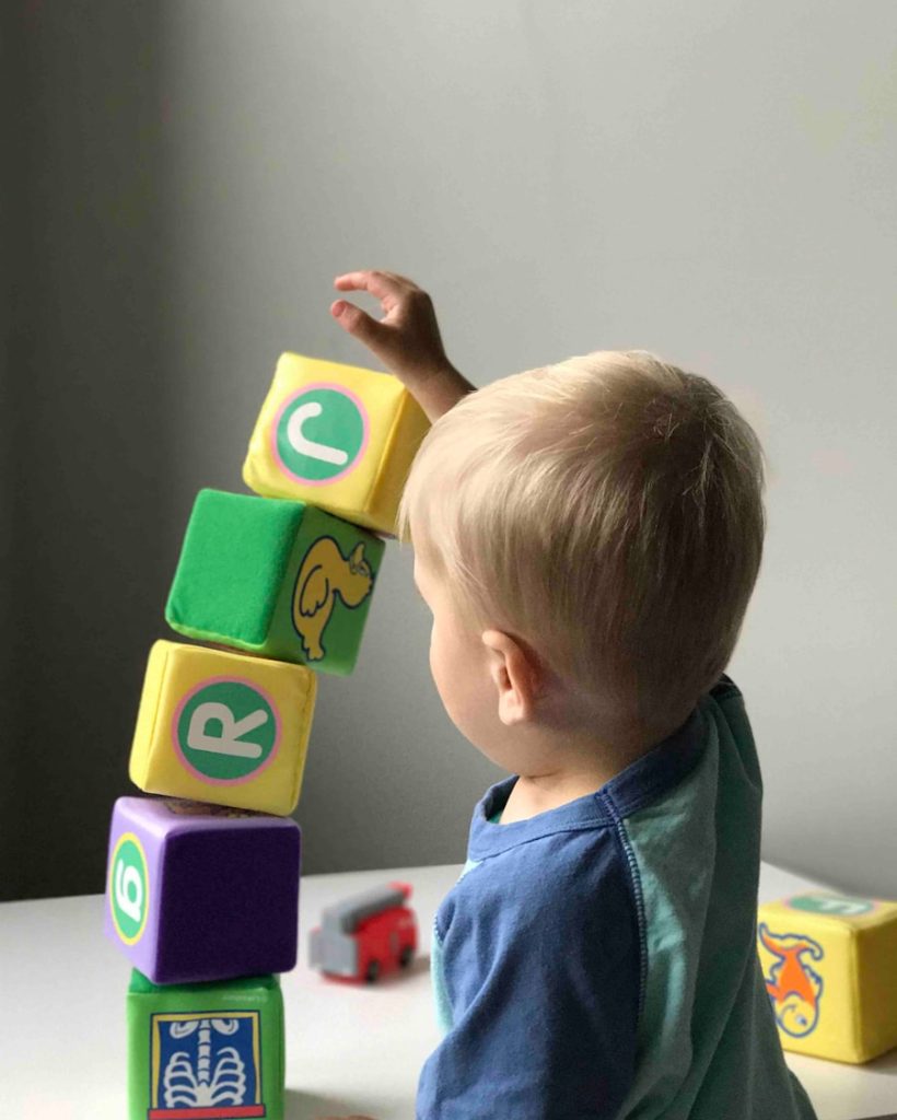 boy playing cube on white wooden table